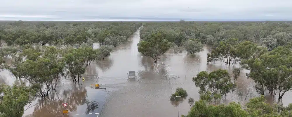 Flooded outback road near Thargomindah, Queensland, with Road Closed signs, showing how remote council sites get cut off